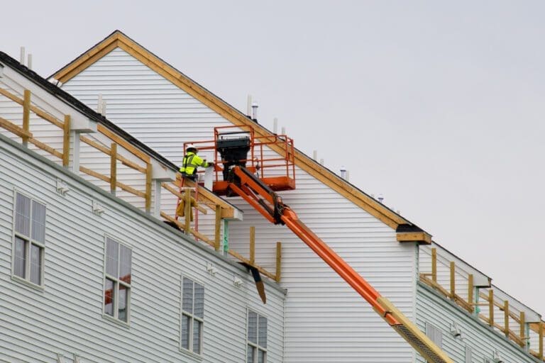 a worker installs panels siding on the facade of the house